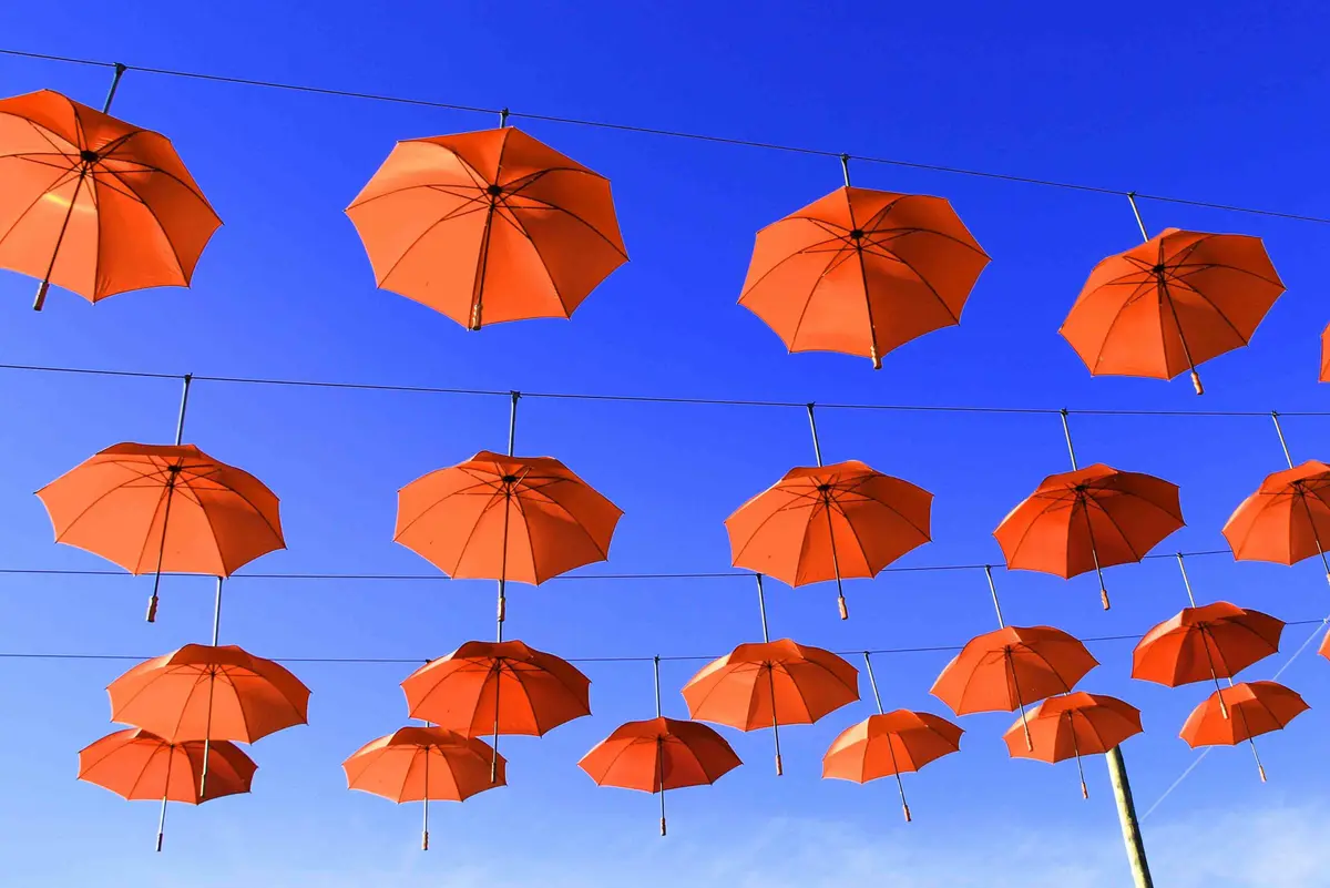 Guarda-chuvas laranja suspensos contra o céu azul em Canela